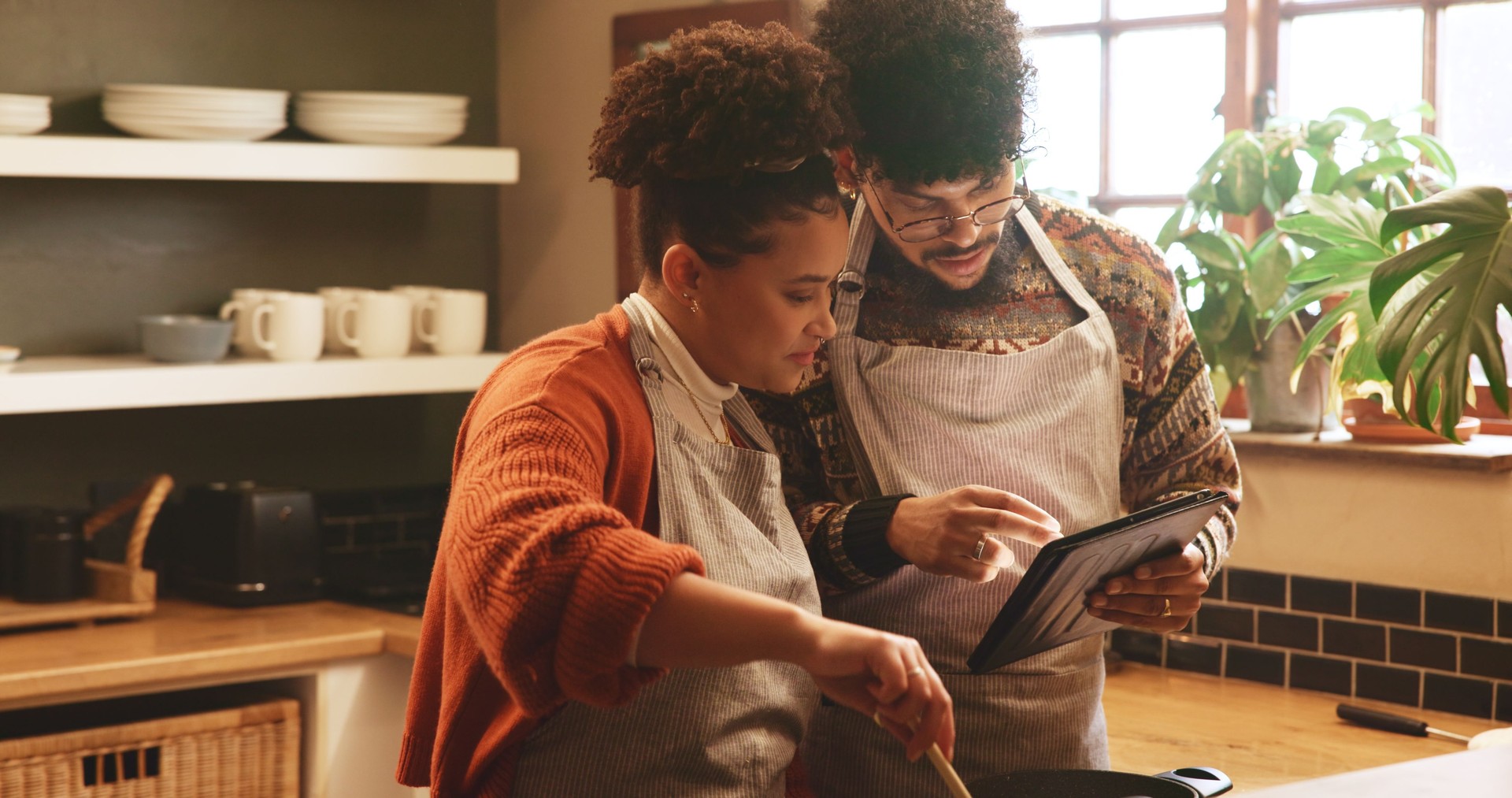 Couple, tablet and cooking in kitchen with pot for recipe, video or guide for meal prep in home. People, man and woman with digital touchscreen, app or partner for food, nutrition or diet in house